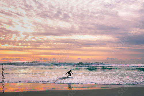 Young man skimboarding as a silhouette against a dramatic sunset sky photo