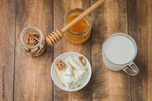 Healthy breakfast background. Honey, milk, cottage cheese and walnut on a wooden background. Top view.