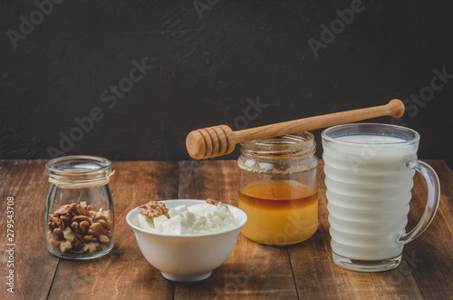 Healthy breakfast background. Honey, milk, cottage cheese and walnut on a wooden background.