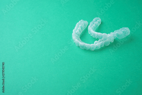 Tooth whitening caps on a green background, side view