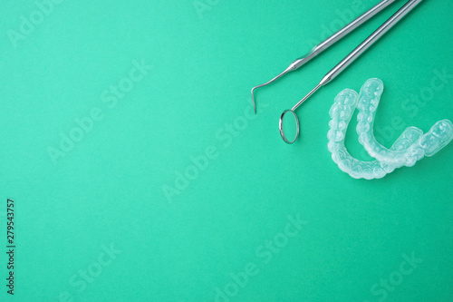 Teeth whitening on a green background and dental metal tools