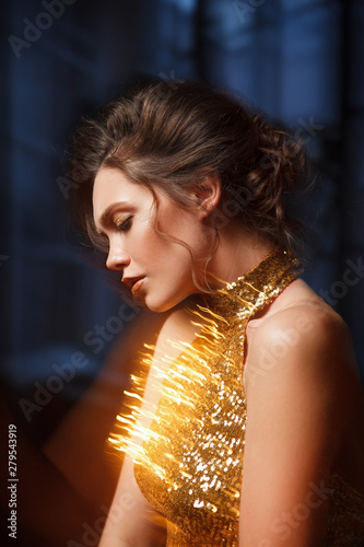 Beautiful elegant woman in a luminous dress, mixed light.
