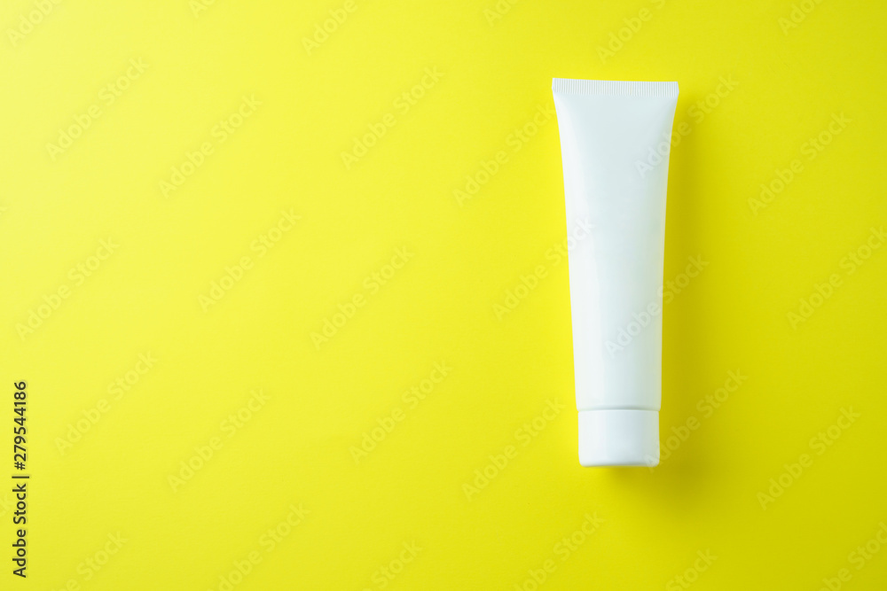 White tube with cream on a yellow background, top view White tube with cream on a yellow background, top view
