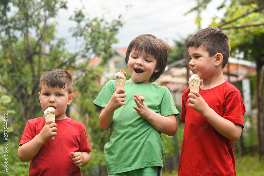 Three happy little boy eating ice cream. Closeup of children eating ice cream in the park Three happy little boy eating ice cream. Closeup of children eating ice cream in the park