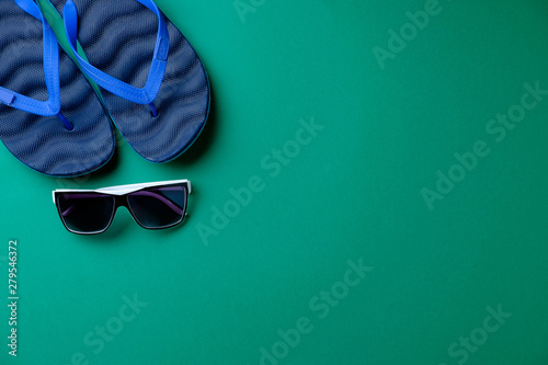 Beach slippers and sunglasses on a green background  a place for the inscription
