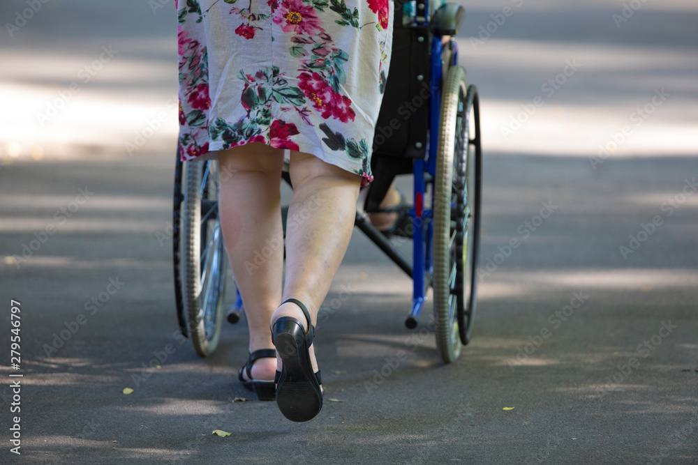 Naklejka premium man pushing wheeling wheelchair with a sick person