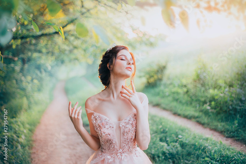 charming goddess of the spring forest stands on a narrow path and breathes in the sweet smell of nature, pleasure in motion, lady with her eyes closed strokes her beautiful neck with her fingertips photo
