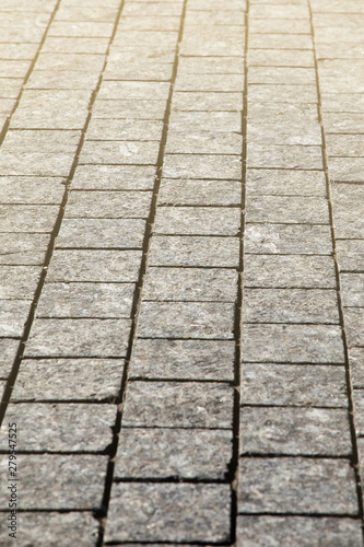 Abstract background of gray cobblestone pavement in light in perspective.