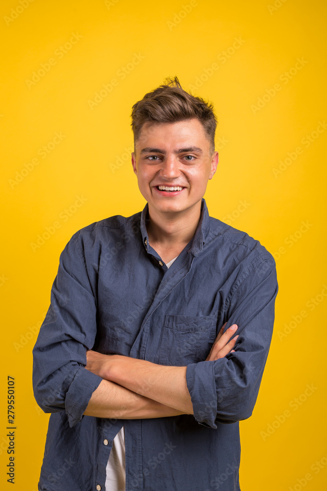 Portrait of happy young man with crossed arms standing over yellow background and looking at camera Portrait of happy young man with crossed arms standing over yellow background and looking at camera