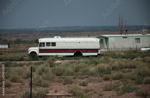 White bus in front of a simple house in American desert