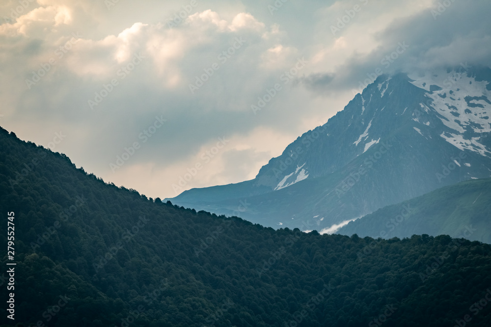 Mountain ranges with green and rocky slopes. Mountains with snowy peaks hidden in the clouds. Mountain ranges with green and rocky slopes. Mountains with snowy peaks hidden in the clouds.