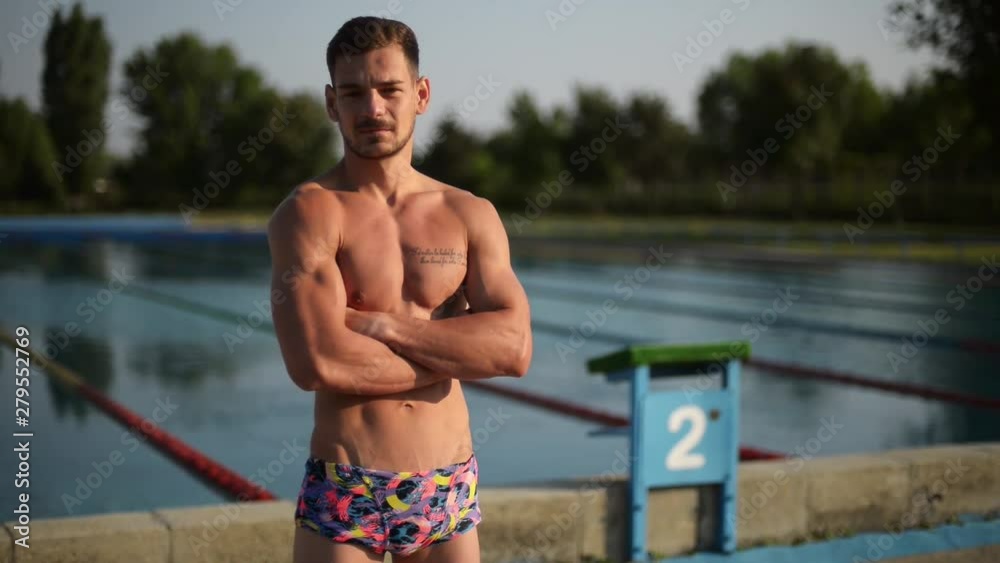 Swimmer standing next to a pool on a sunny morning Swimmer standing next to a pool on a sunny morning