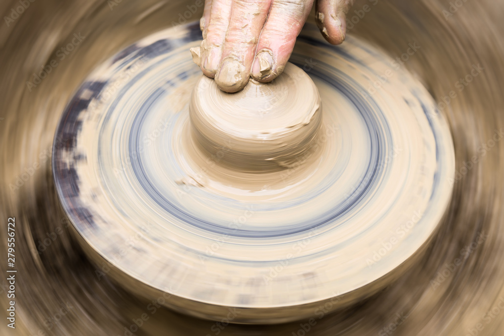 potter's hand and rotating wheel with a wad of clay potter's hand and rotating wheel with a wad of clay