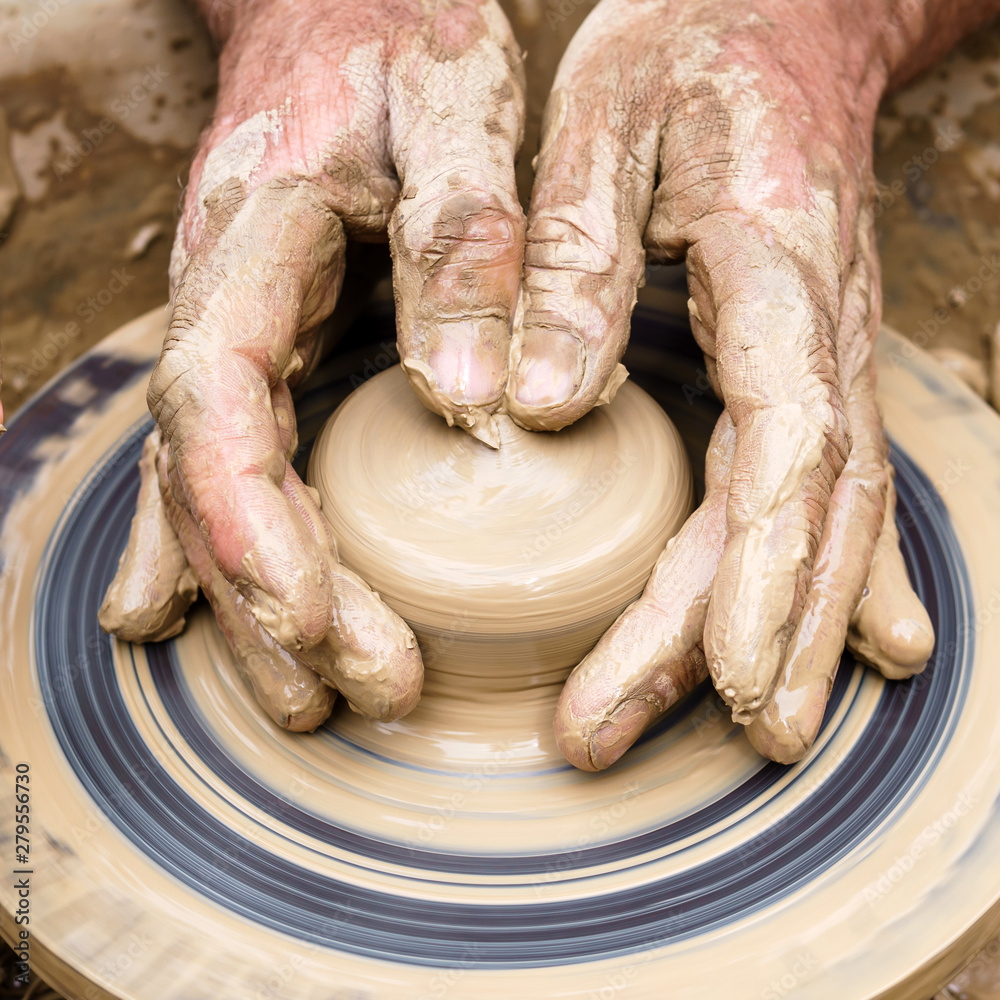 potter’s fingers touch the shapeless piece of clay on the rotating wheel
