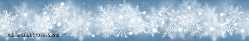 Christmas banner of complex blurred and clear snowflakes in white colors on light blue background. With horizontal repetition