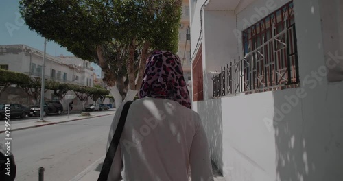 Young woman wearing the hijab walking in the street photo