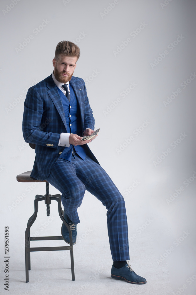 portrait of confident businessman in armchair holding dollar banknotes isolated on grey portrait of confident businessman in armchair holding dollar banknotes isolated on grey
