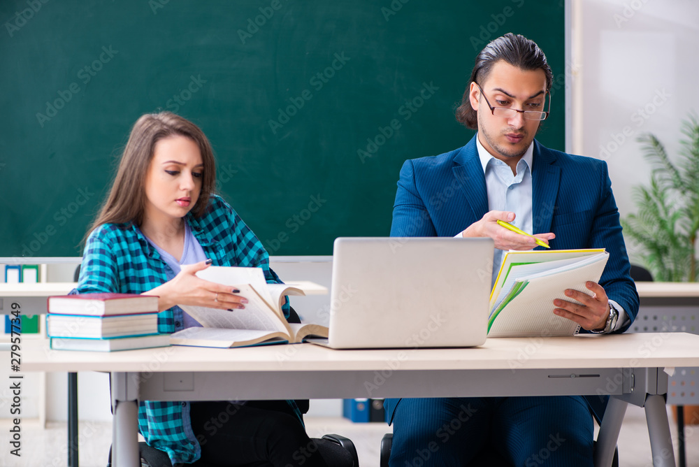 Young handsome teacher and female student in the classroom Young handsome teacher and female student in the classroom