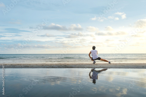 young  man with fit strong body training on beautiful Summer sunset beach sand running barefoot in sport well being and healthy lifestyle concept © Tawanboonnak