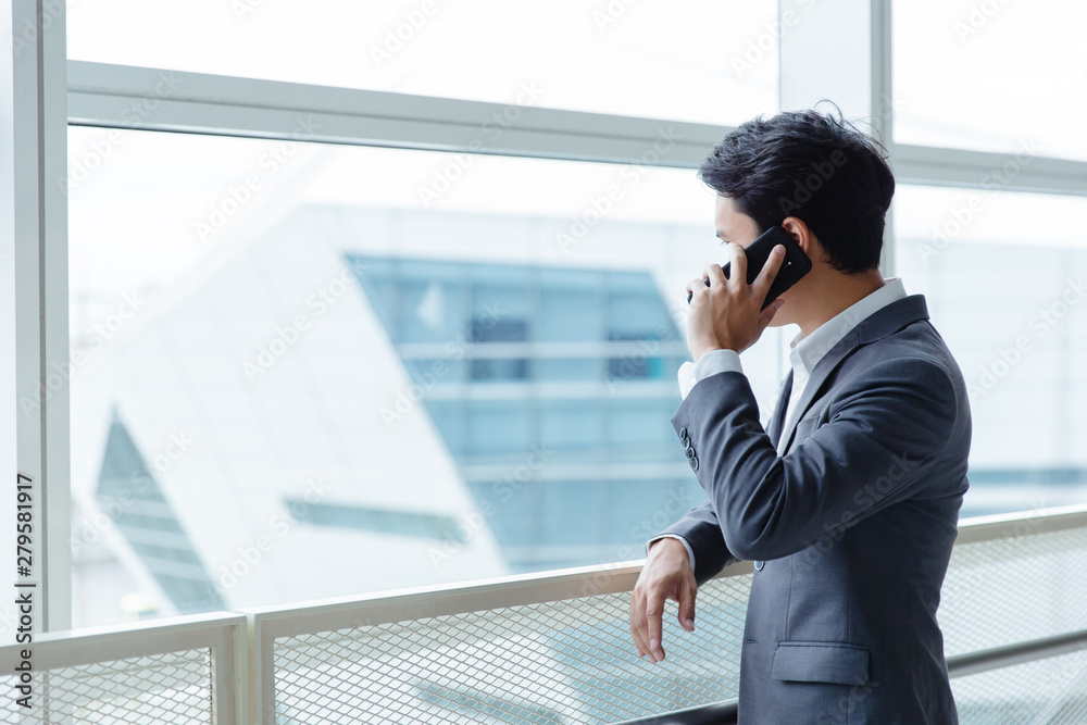 businessman using a cell phone, smiling. Taken in front of a modern office businessman using a cell phone, smiling. Taken in front of a modern office
