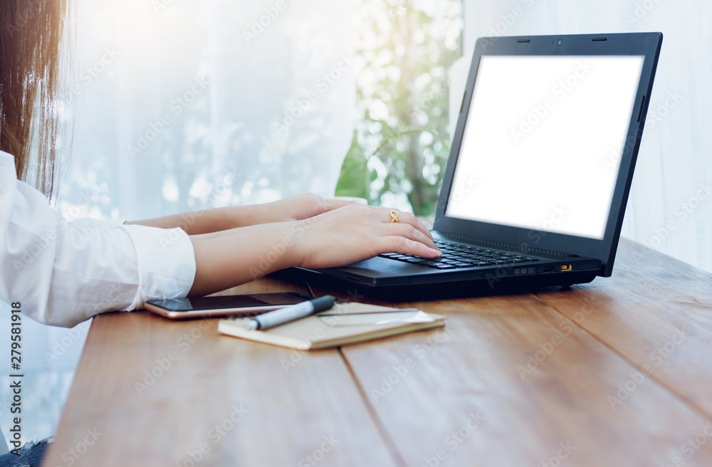 Asian woman using laptop working with smartphone and notebook on wooden table Asian woman using laptop working with smartphone and notebook on wooden table