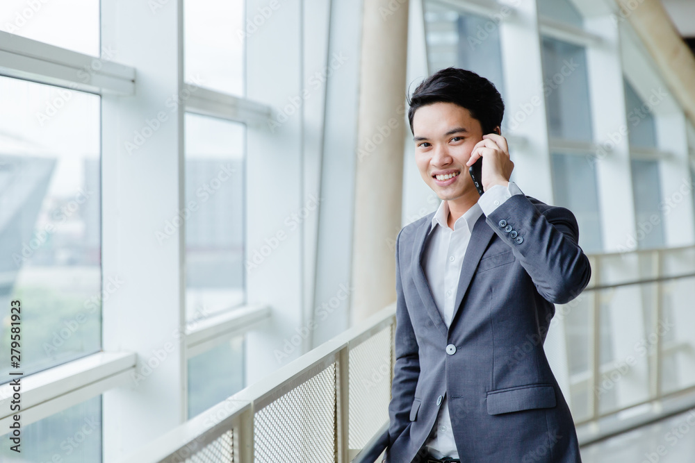 businessman using a cell phone, smiling. Taken in front of a modern office businessman using a cell phone, smiling. Taken in front of a modern office