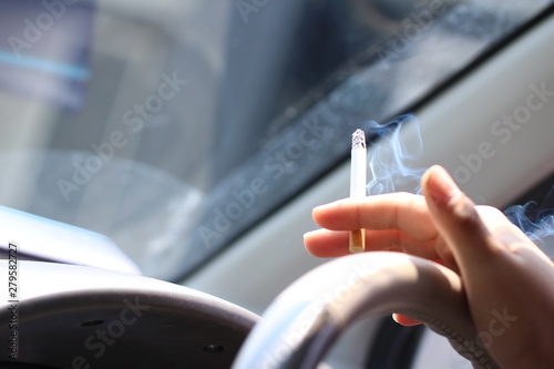 運転をしながら車内で喫煙をする男性の手元。