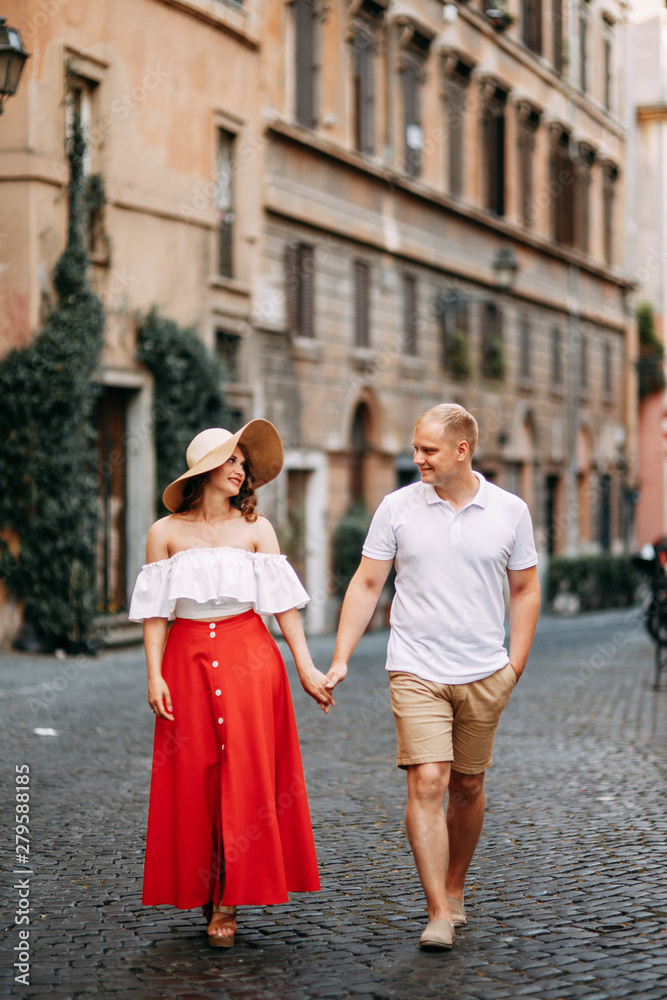 Naklejka premium Stylish loving couple walking and laughing. Wedding shooting on the streets of Rome, Italy.