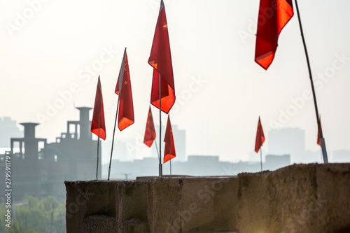 Chinese flags lining Kashgar's renovated Old City wall, with modern buildings in the background.  Kashgar, Xinjiang, China. photo
