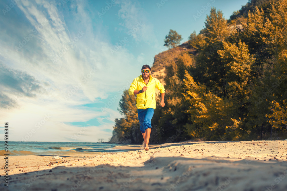 bearded athlete runs along the sandy beach. active lifestyle