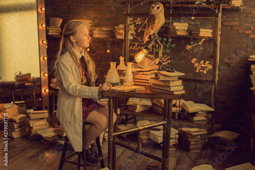 preteen girl studying in the lab with owl sitting on the lamp