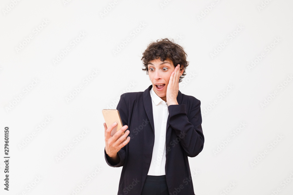 Surprised businesswoman holding smartphone. Shocked middle aged woman in formal wear holding cell phone isolated on grey background. Technology concept Surprised businesswoman holding smartphone. Shocked middle aged woman in formal wear holding cell phone isolated on grey background. Technology concept