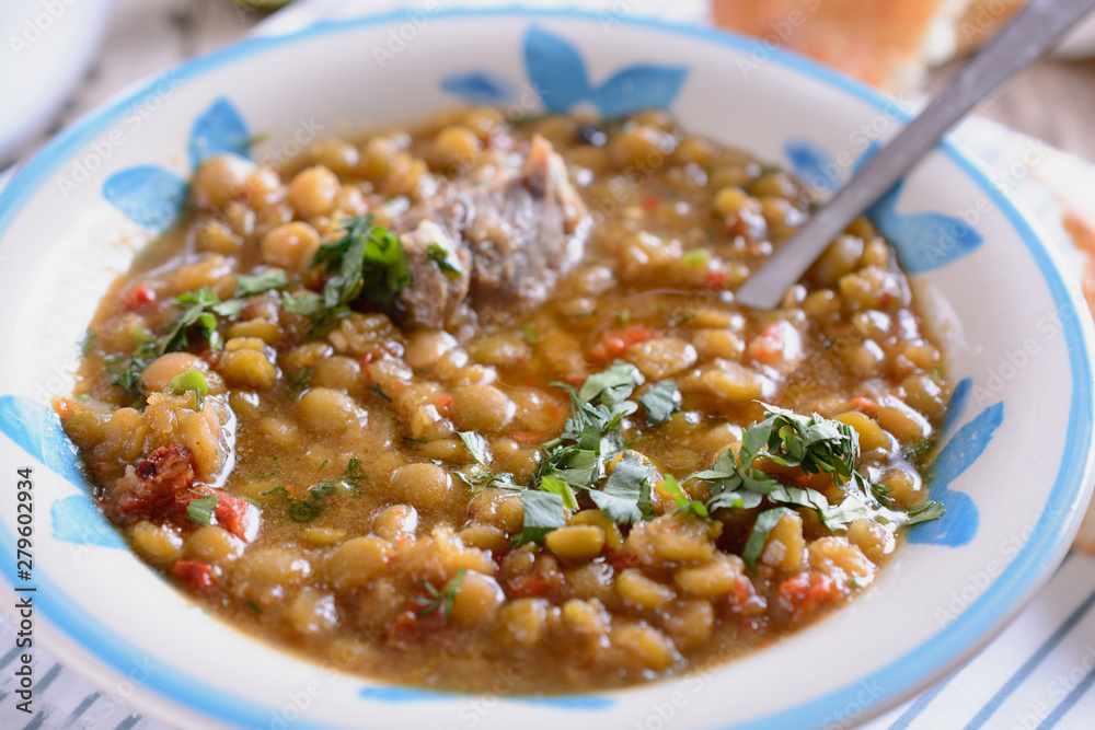 Mixed legumes and peas soup with meat and some greenary at a bowl, close up