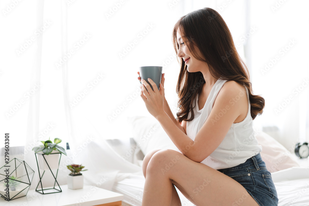 Woman drinking coffee in bedroom in the morning Woman drinking coffee in bedroom in the morning