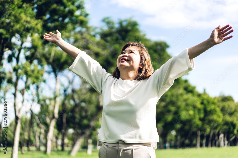 Portrait of happy senior adult elderly asia women smiling standing and stretch her arms relax and enjoy with nature fresh air in the park
