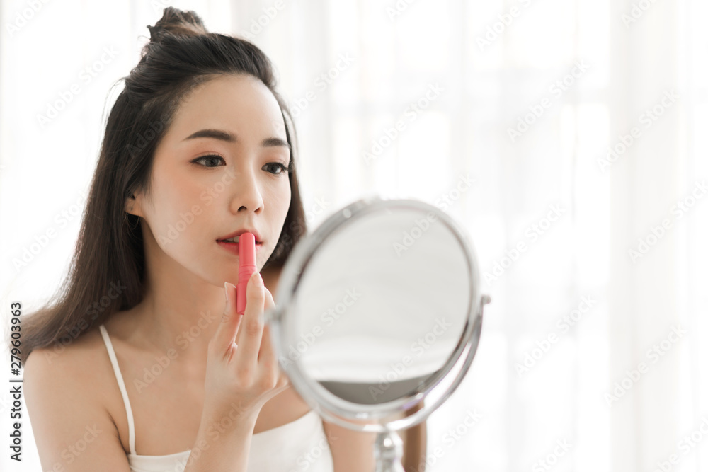 Smiling beautiful woman fresh healthy skin looking on mirror and enjoying applying lips with red lipstick at home.facial beauty and cosmetic concept Smiling beautiful woman fresh healthy skin looking on mirror and enjoying applying lips with red lipstick at home.facial beauty and cosmetic concept