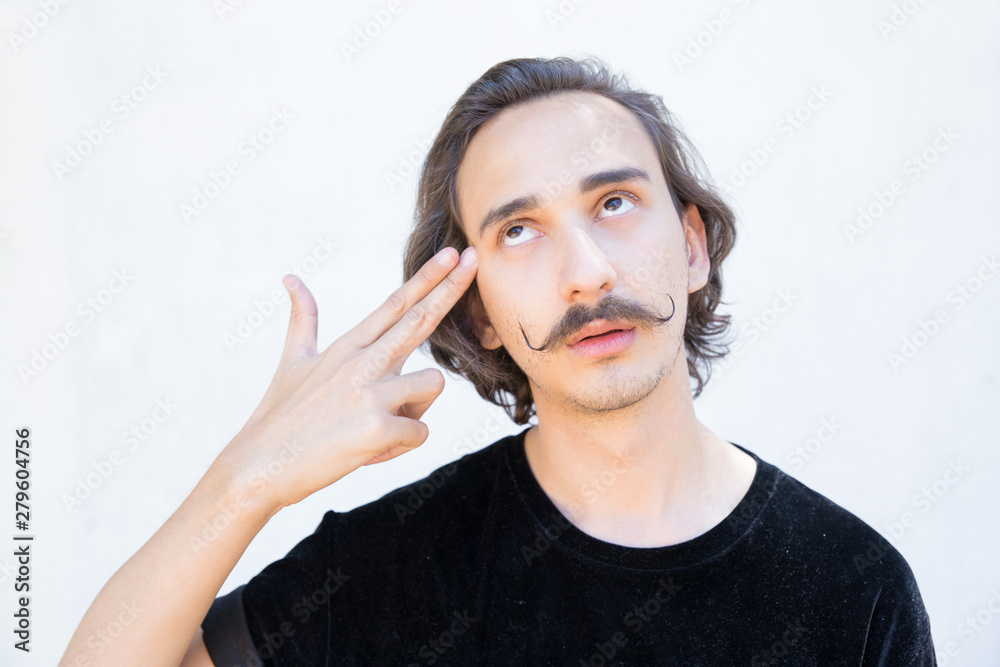 Tired man with mustache holding fingers near temple. Handsome young man holding hand in gun gesture. Body language concept Tired man with mustache holding fingers near temple. Handsome young man holding hand in gun gesture. Body language concept