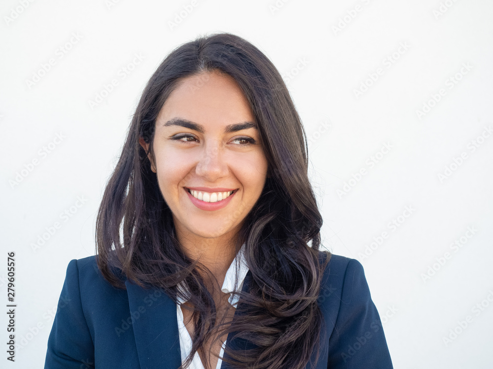 Cheerful female office worker looking at copy space away and smiling. Front portrait of beautiful black haired young Latin woman wearing formal jacket over white background. Human emotions concept Cheerful female office worker looking at copy space away and smiling. Front portrait of beautiful black haired young Latin woman wearing formal jacket over white background. Human emotions concept