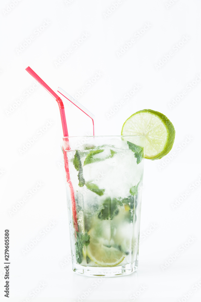 Mojito cocktail in a transparent glass with ice. Recipe for exotic drinks with mint, lime and white rum. Glass with a cocktail on a white background in the rays of the sun.