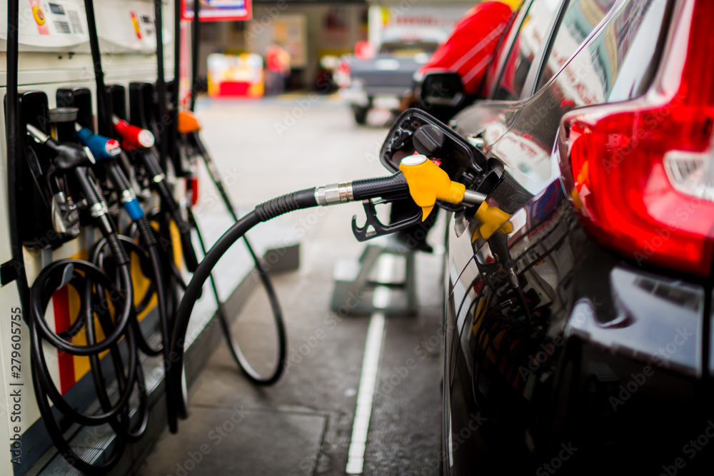 Fototapeta premium Refilling the car with fuel at the gas station and blurry staff background, black car in gas station, refilling the car with fuel at the refuel station, the concept of fuel energy, Blurry image for