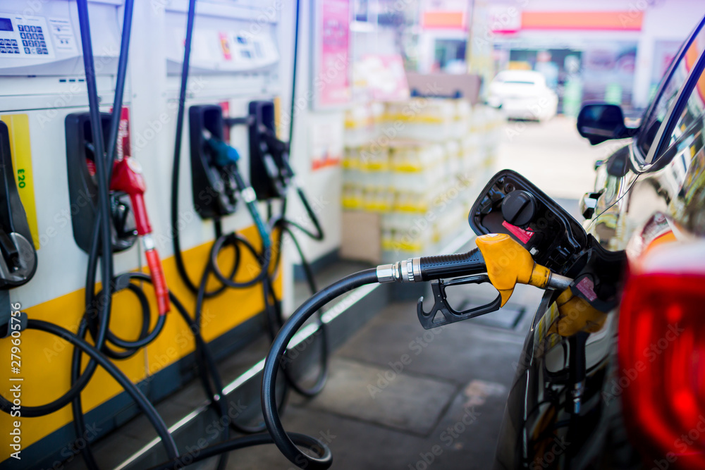 refilling the car with fuel at the gas  station and blurry staff background, black car in gas station, refilling the car with fuel at the refuel station, the concept of fuel energy, selective focus.