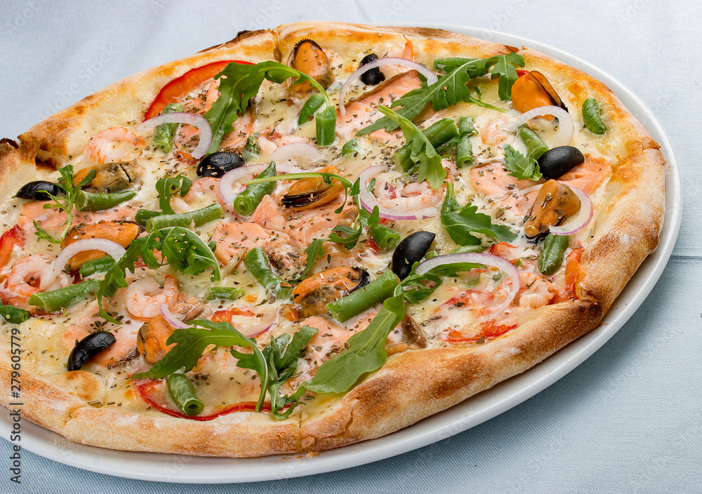 Delicious hot pizza with salmon, mussels, olives, tomatoes and various spices. On white background