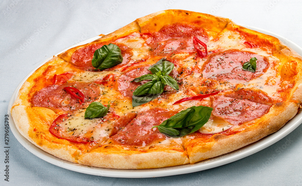 Delicious hot pizza with salami, cheese, tomatoes and various spices. On white background