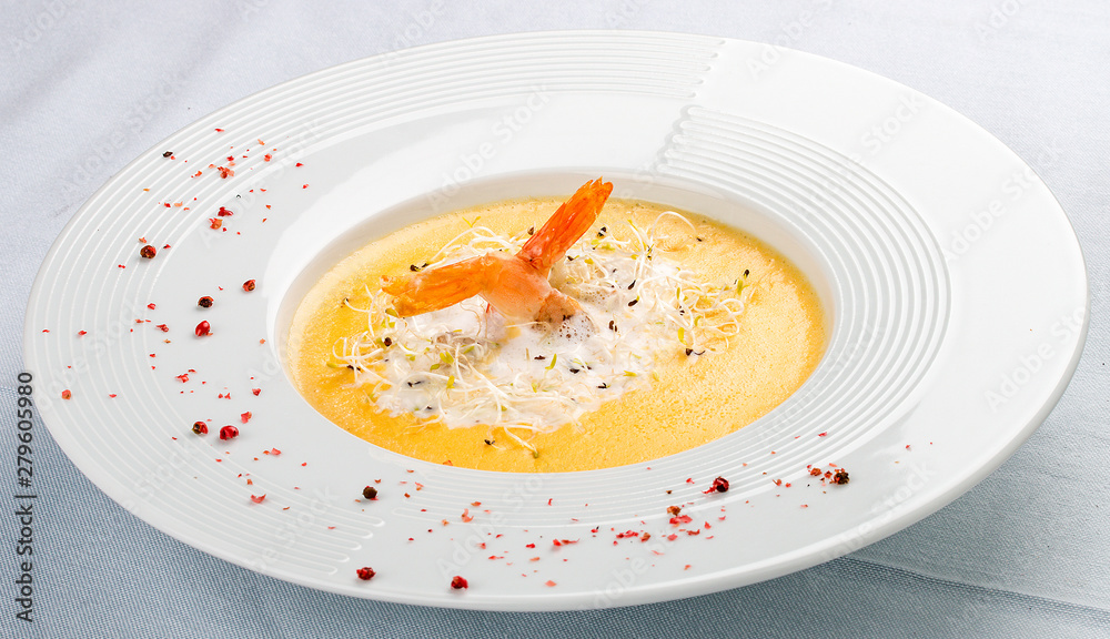 Cheese cream soup with parmesan and shrimp on a white plate Cheese cream soup with parmesan and shrimp on a white plate