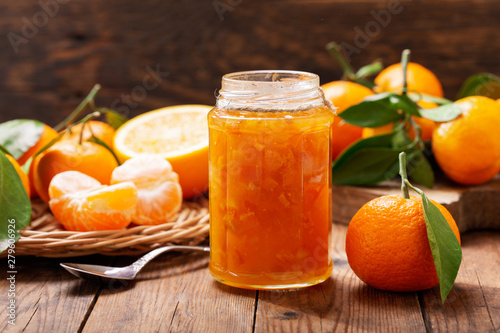 glass jar of orange tangerine or mandarin jam with fresh fruits