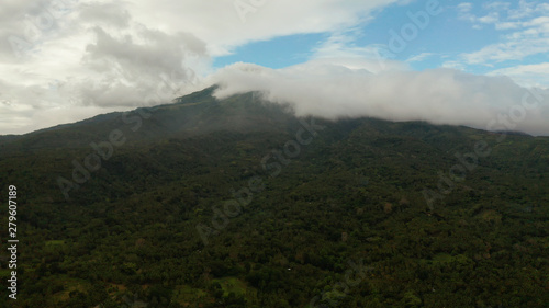 Aerial view of tops of the mountains covered with clouds in the evening Camiguin, Philippines. Mountain landscape on tropical island with mountain peaks covered with forest. Slopes of mountains with