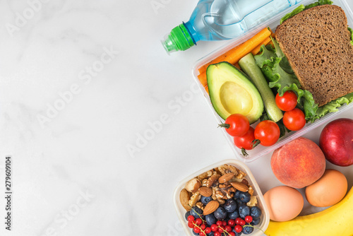 Valokuva healthy lunch boxes with sandwich, vegetables, nuts, berries, banana, eggs, avoc