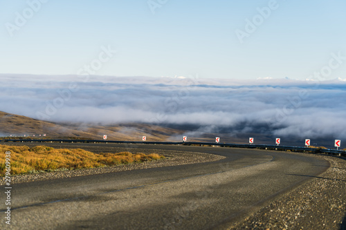 Curve asphalt road with beautiful nature sea of cloud and golden yellow grass in autumn in cloudy blue sky through national park south Patagonia, Argentina and Chile photo