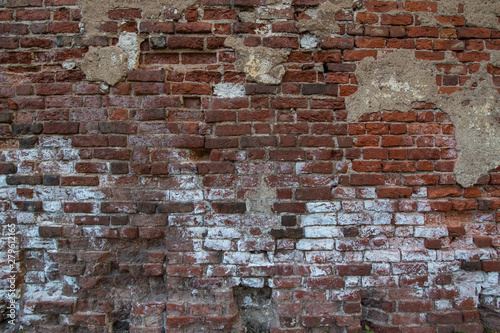 wall of old red brick with remnants of fallen plaster