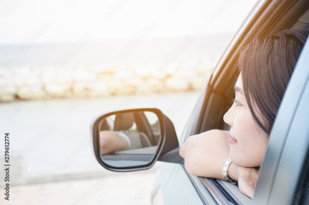 Naklejka premium .The woman sat looking at the sea from the front of the car happily. Holiday concept